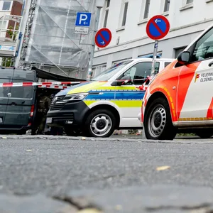 Einsatzfahrzeuge von Polizei und Feuerwehr stehen vor einem Haus in der Innenstadt.