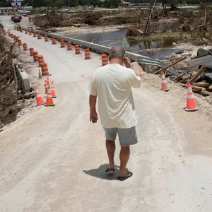 Ein Anwohner geht nach den Überschwemmungen in Kerrville die Brücke über den Guadalupe River entlang.