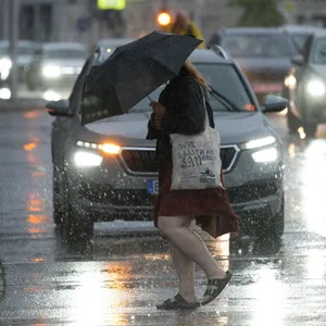 Eine Frau läuft mit einem Regenschirm über eine Straße