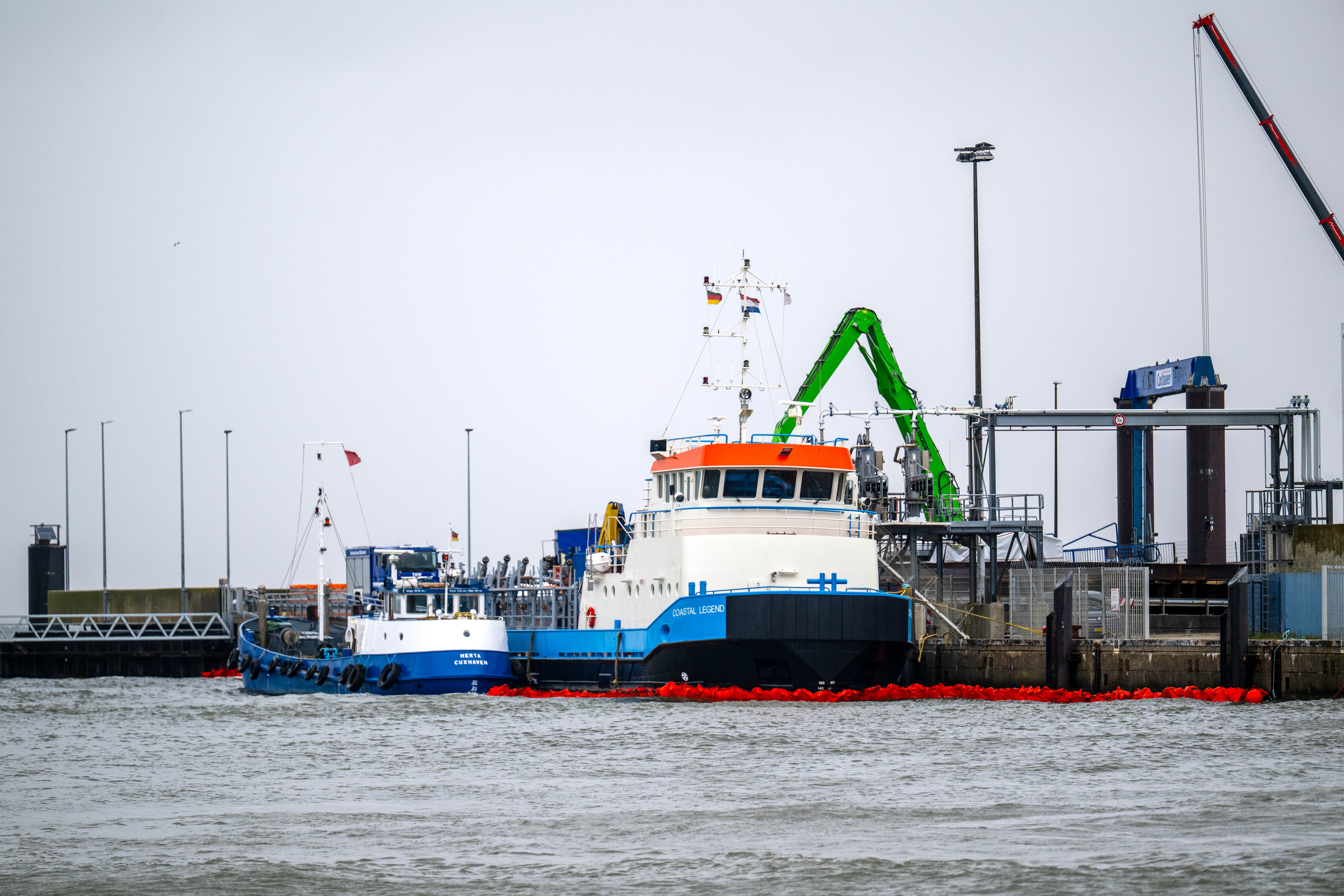 Ölsperren sind im Hafenbecken vor dem Offshore-Versorgungsschiff „Coastal Legend“ ausgelegt.