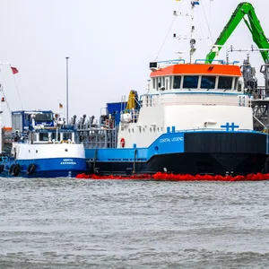 Ölsperren sind im Hafenbecken vor dem Offshore-Versorgungsschiff „Coastal Legend“ ausgelegt.