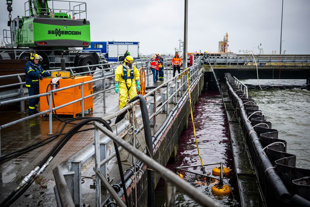 Mit Spezialausrüstung bekämpfen Einsatzkräfte das ausgelaufene Öl im Hafen.