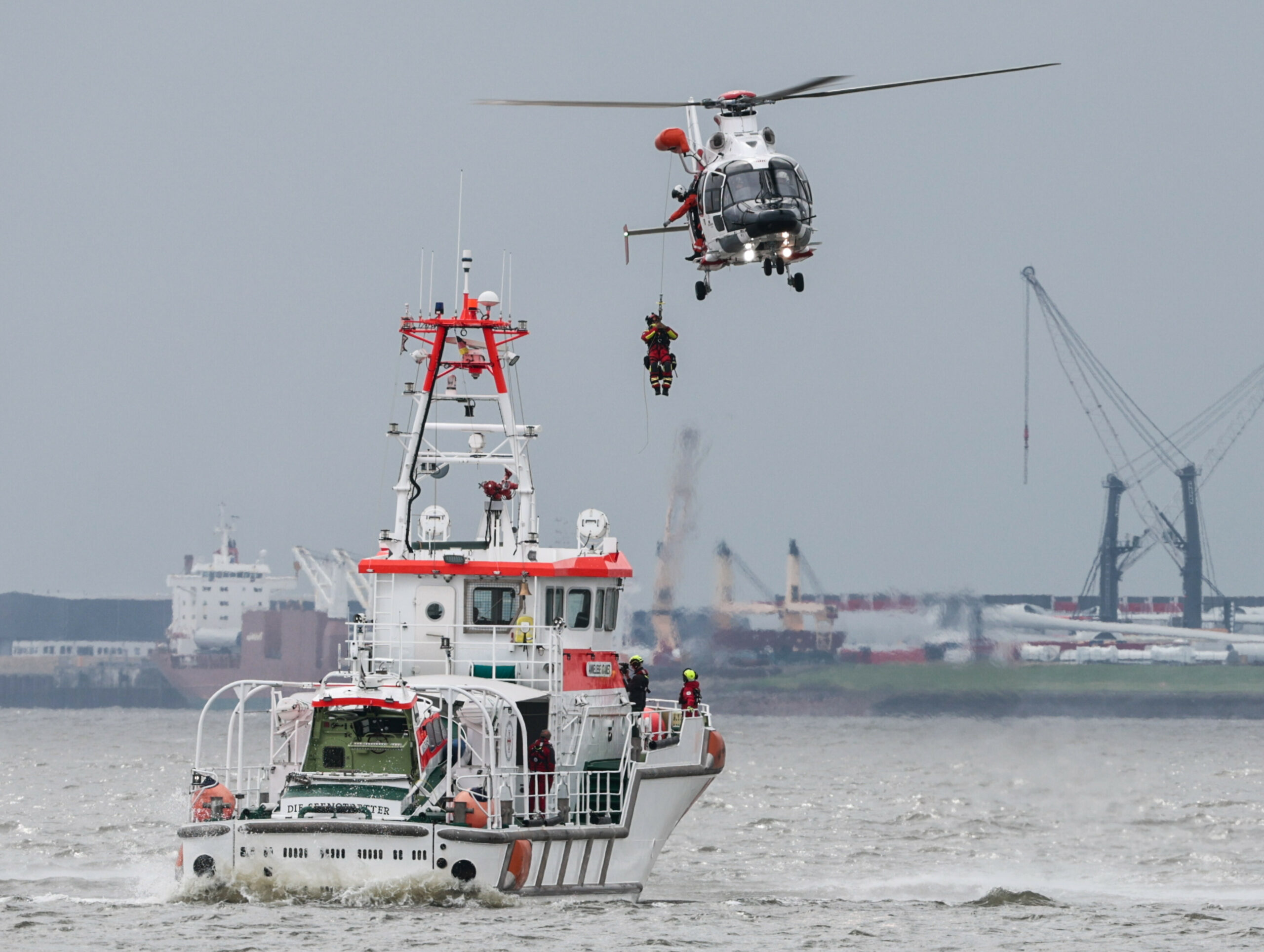 Ein Rettungshubschrauber lässt am Tag der Seenotretter auf der Elbe bei einer Winschübung einen Helfer zum Seenotrettungskreuzer Anneliese Kramer herab.