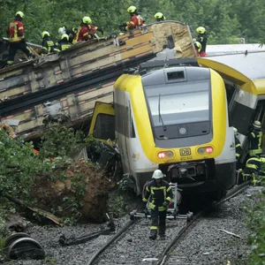 Rettungskräfte stehen vor dem entgleisten Zug.