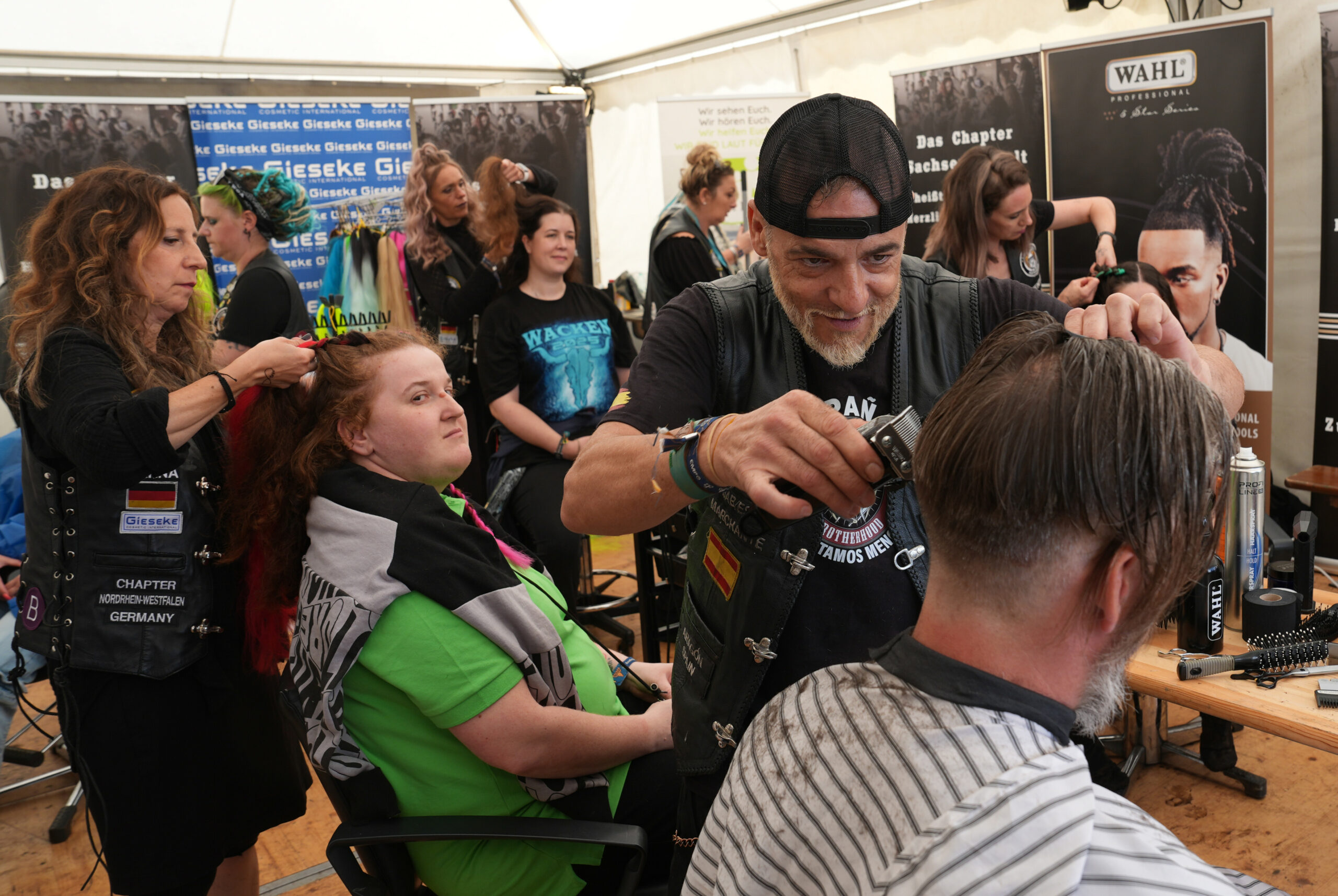 Friseure vom „Barber Angels Brotherhood“ frisieren auf dem Festivalgelände des Wacken Open Airs (WOA) Metalfans.