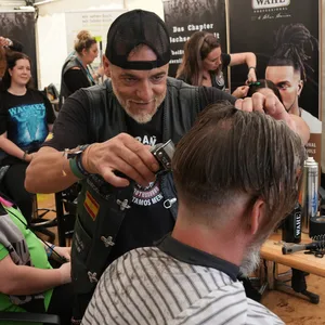 Friseure vom „Barber Angels Brotherhood“ frisieren auf dem Festivalgelände des Wacken Open Airs (WOA) Metalfans.