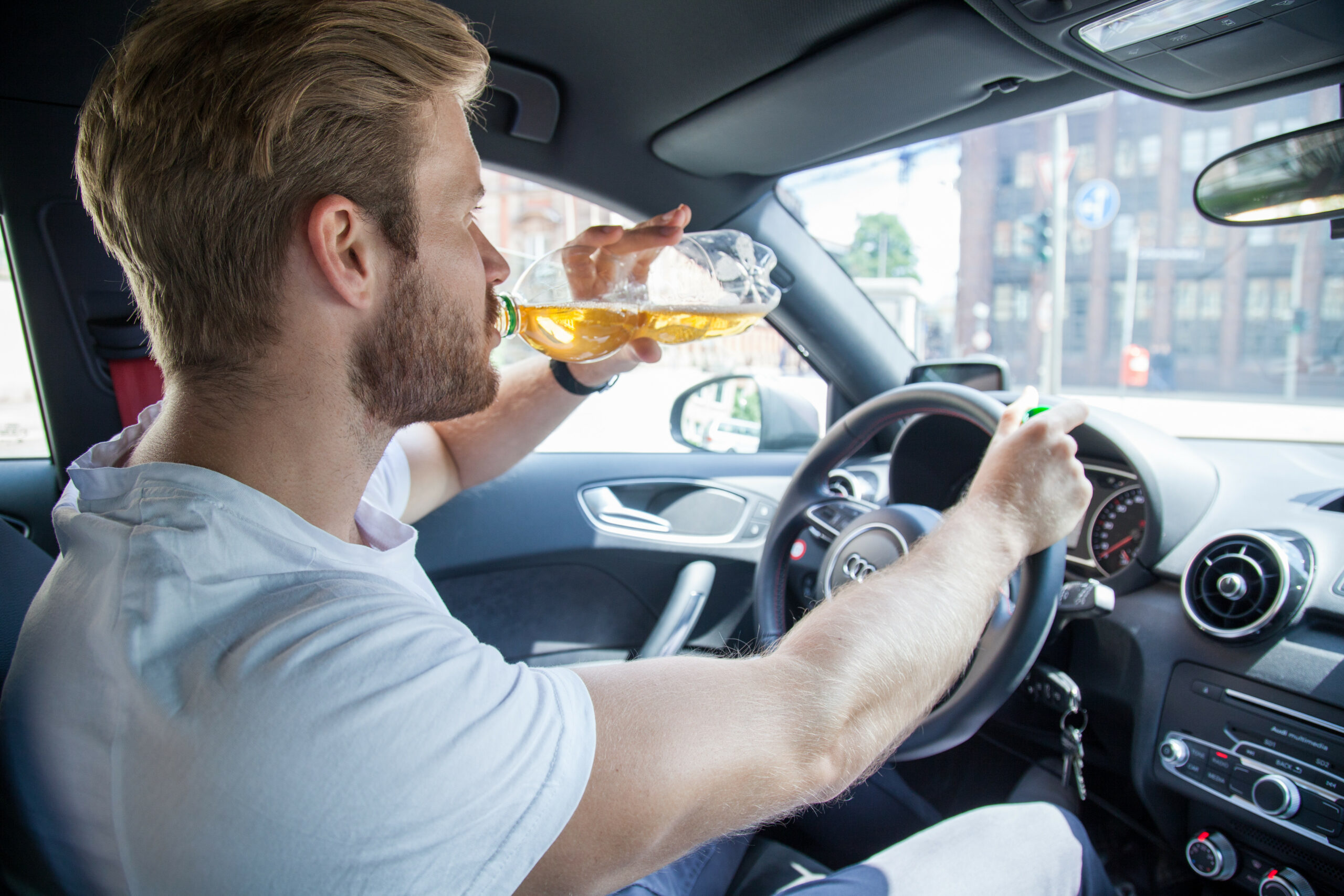Junger Fahrer an Lenkrad mit Flasche