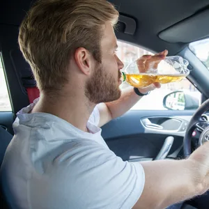 Junger Fahrer an Lenkrad mit Flasche