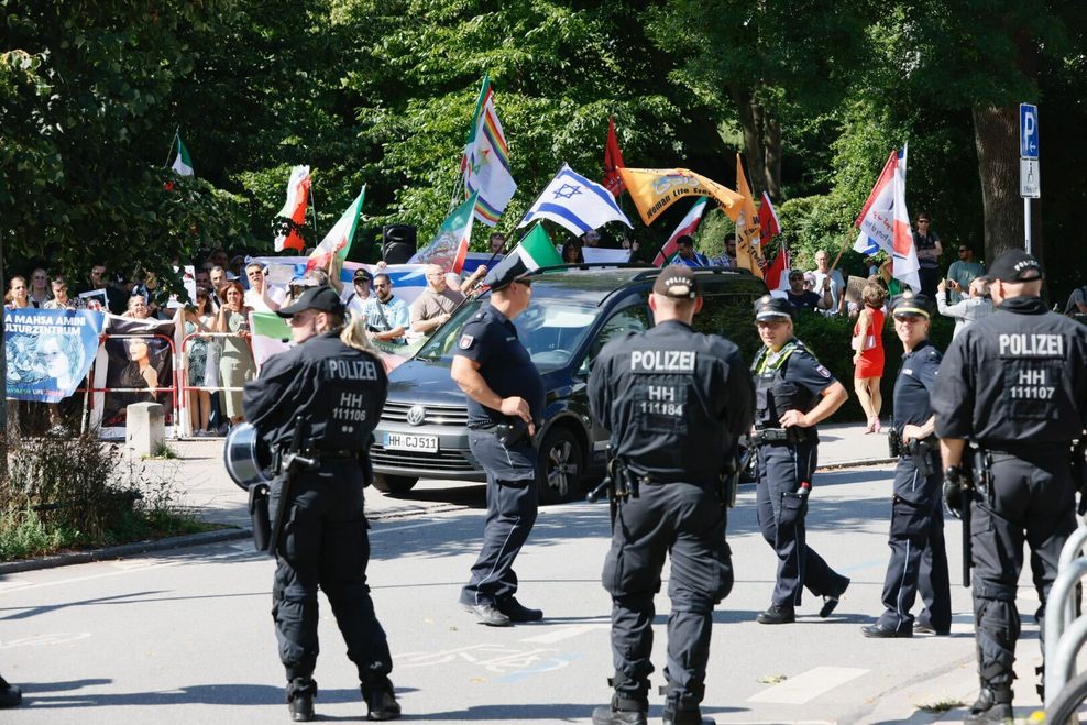 Polizisten stehen vor einer Gruppe an Gegendemonstranten.