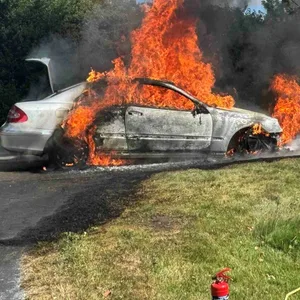 Ein Anwohner versucht, das brennende Auto in Guderhandviertel mit einem Gartenschlauch zu löschen.