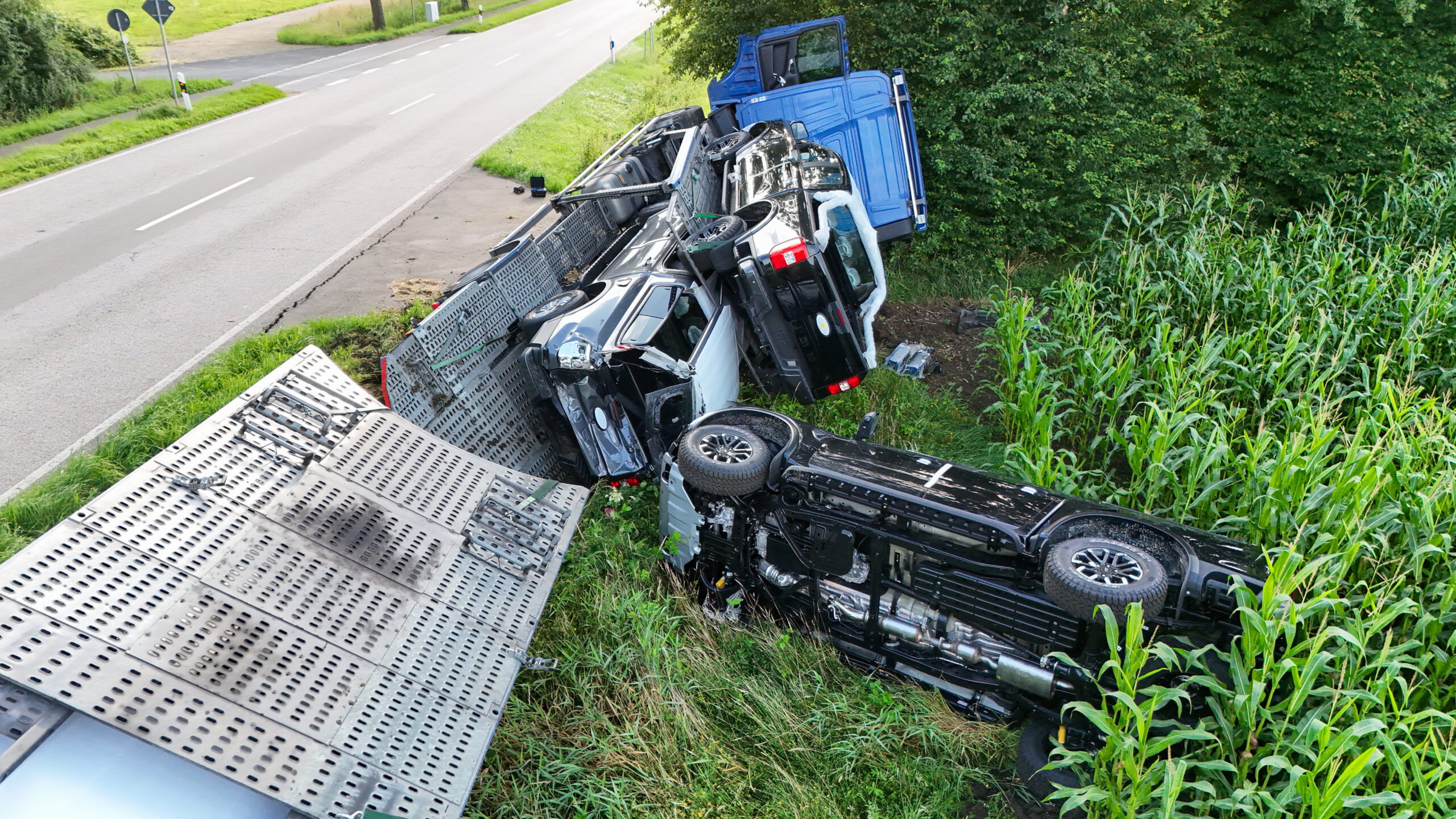 Der Autotransporter liegt auf der Seite. Ein Auto ist herunter gekippt.