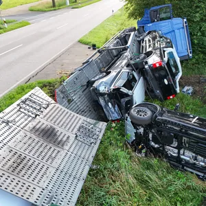 Der Autotransporter liegt auf der Seite. Ein Auto ist herunter gekippt.