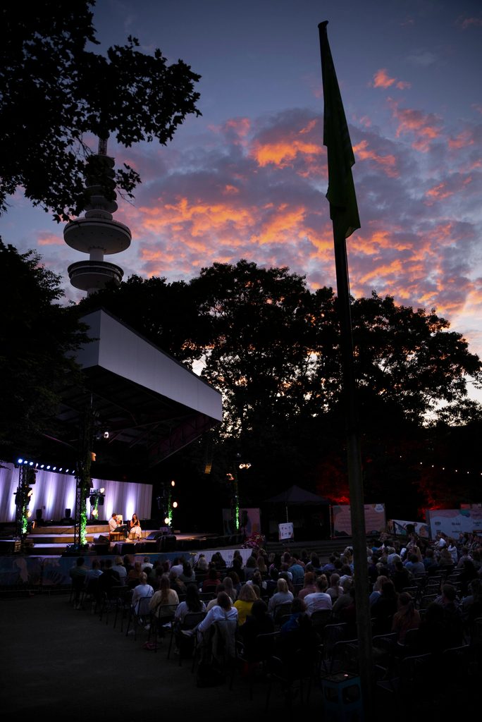 Menschen sitzen vor dem Musikpavillon in Planten un Blomen.