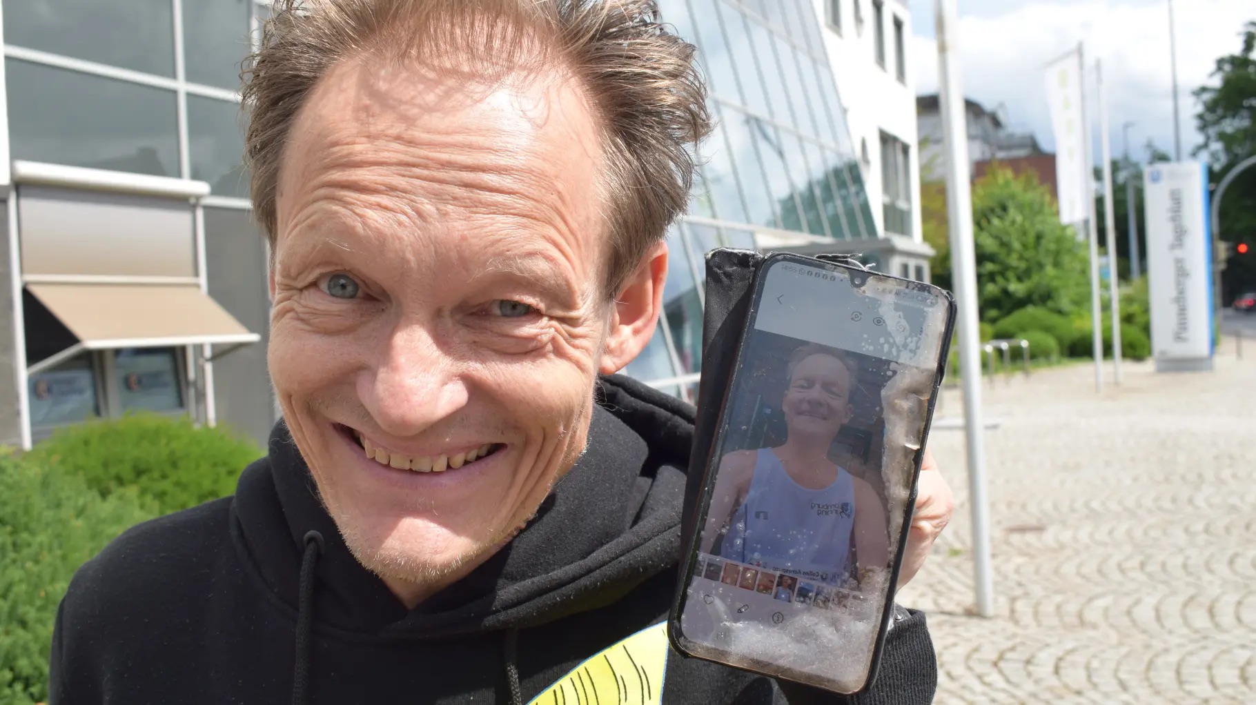 Mann hält ein Foto von sich selbst lächelnd in die Kamera