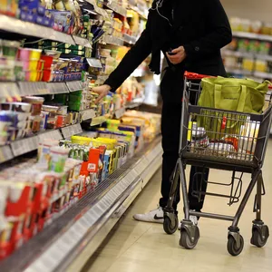 Ein Kunde bedient sich im Supermarkt-Regal.