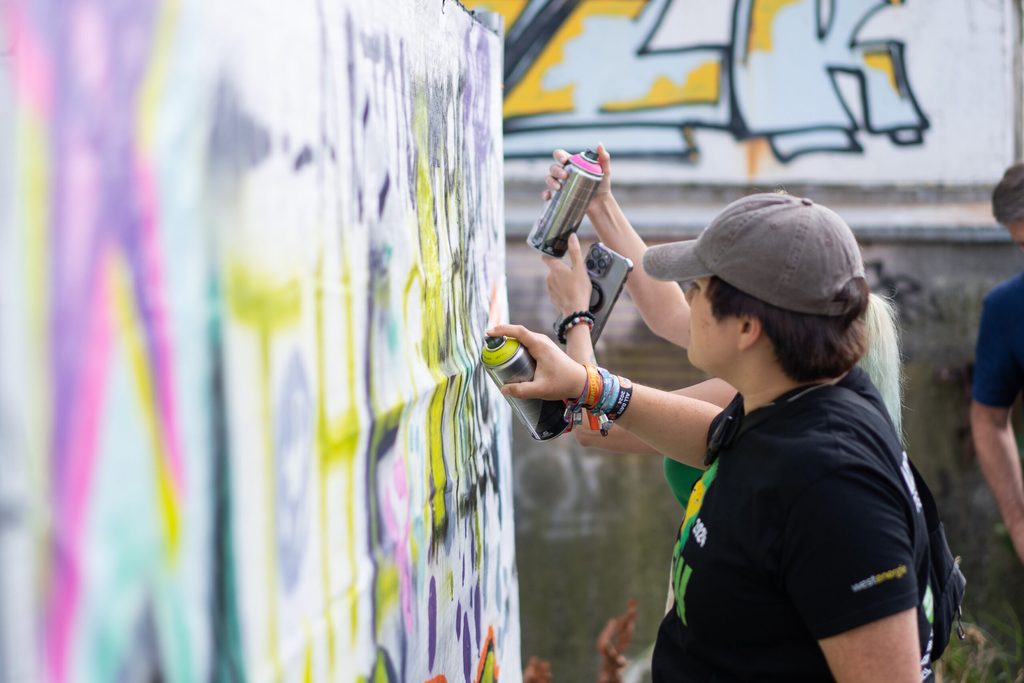 Menschen sprühen Graffiti auf eine Wand.