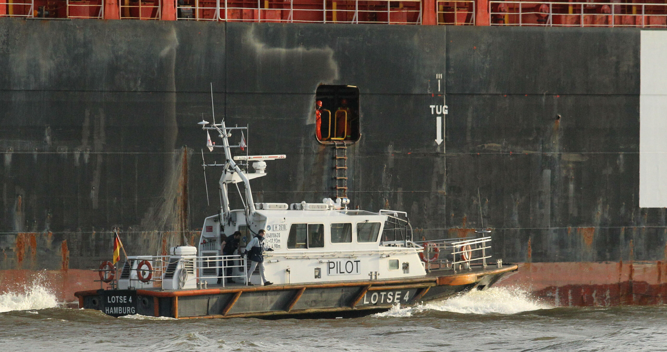 Das Lotsenboot Lotse 4 fährt neben einem Containerschiff entlang. Altona Hamburg *** Pilot boat pilot 4 sails next to a