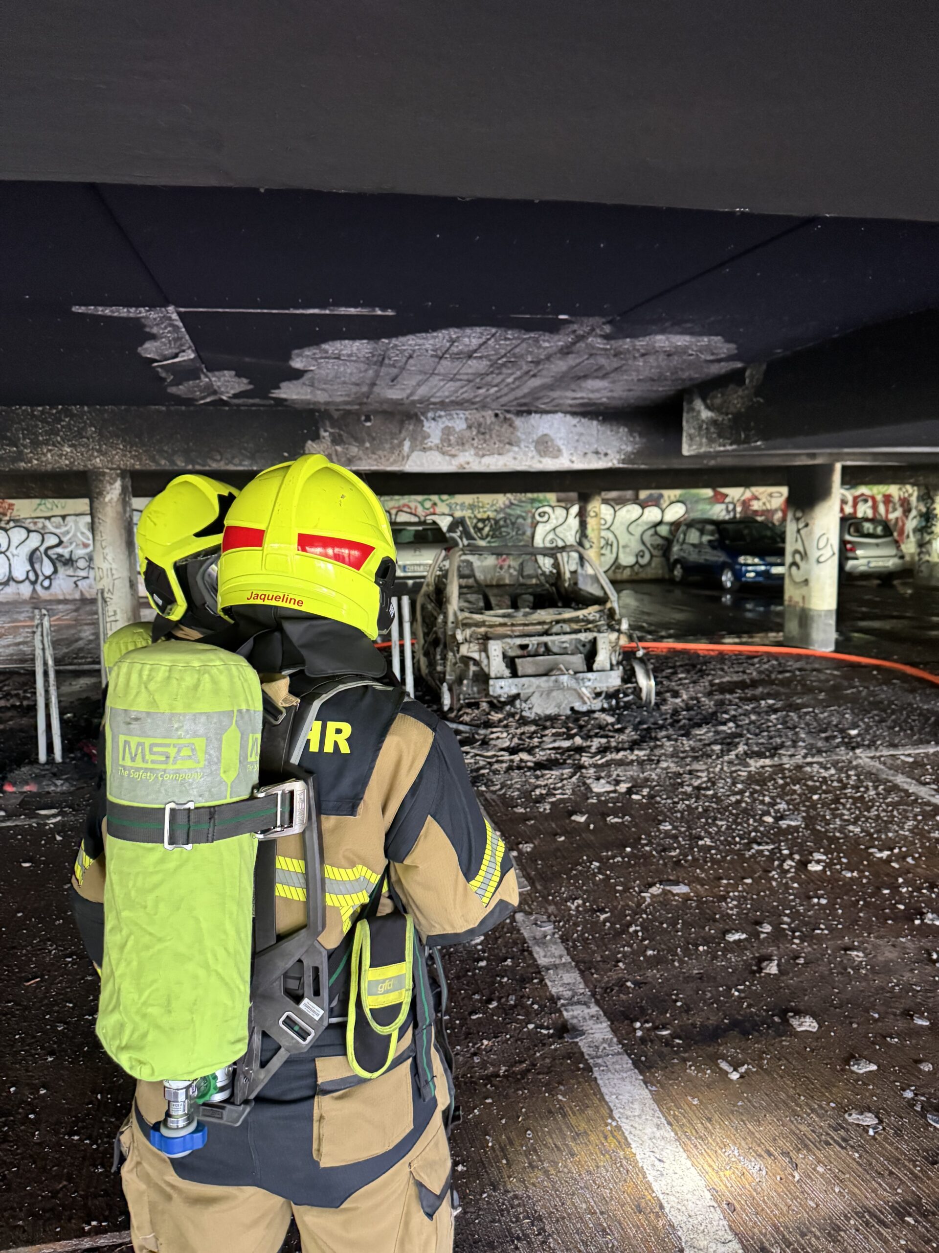 Ein Feuerwehrmann vor dem ausgebrannten Fahrzeug in Wedel.