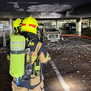 Ein Feuerwehrmann vor dem ausgebrannten Fahrzeug in Wedel.