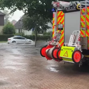 Ein Auto fährt auf einer überflutete Straße.