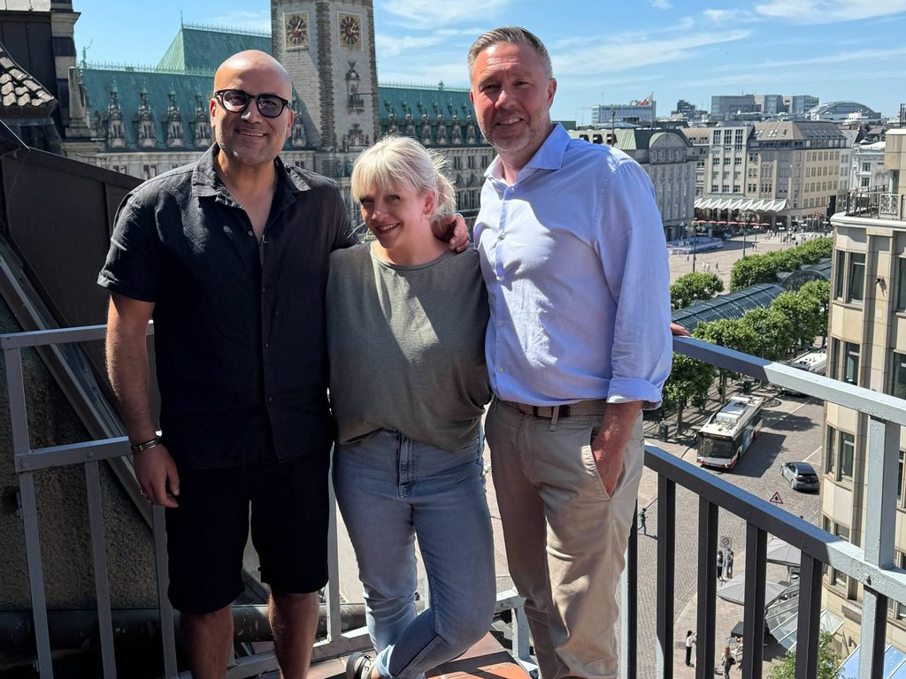 Kemal Üres, Jill Bittner und Ramin Dibadj auf einem Balkon. Im Hintergrund ist das Rathaus zu sehen.