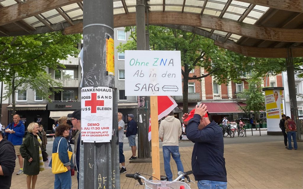 Ein Plakat ist an einem Fahrrad festgemacht. Darauf steht: „Ohne ZNA – Ab in den Sarg“.