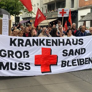 Demonstranten tragen ein Banner mit der Aufschrift: „Krankenhaus Groß-Sand muss bleiben“