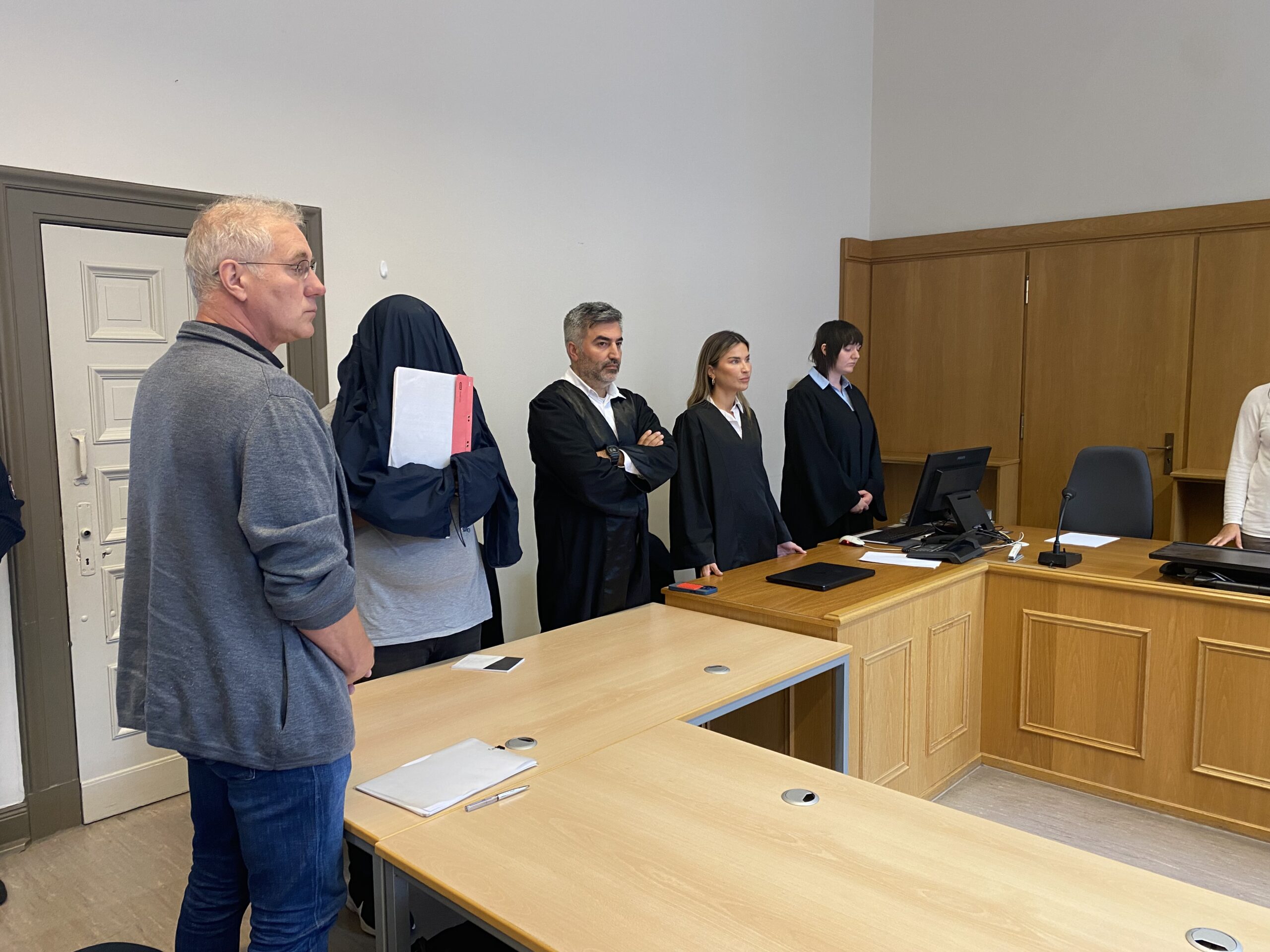 Der Angeklagte Ernest H. steht mit einer Jacke über dem Kopf neben seinem Verteidiger.