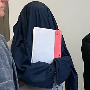 Der Angeklagte Ernest H. steht mit einer Jacke über dem Kopf neben seinem Verteidiger.