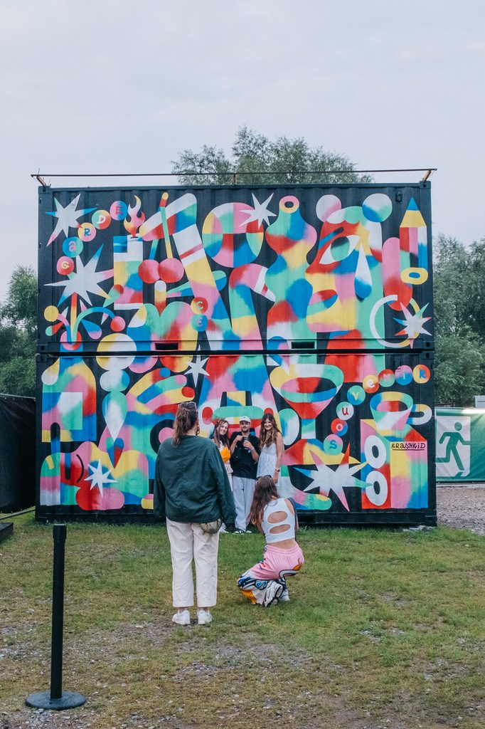 Menschen stehen vor einem bunten Container.