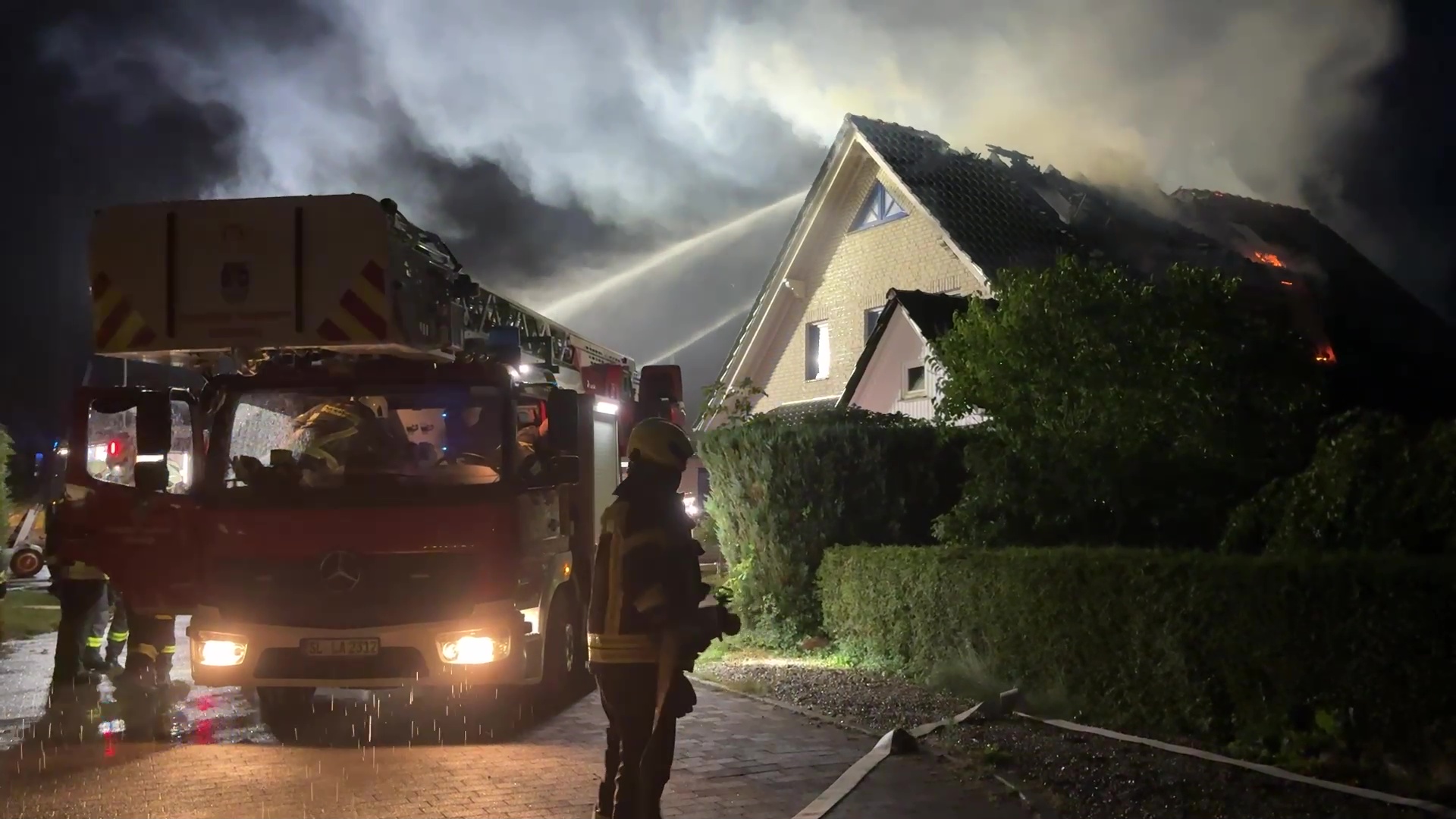 Die Feuerwehr löscht das brennende Dach des Hauses.