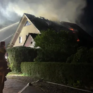 Die Feuerwehr löscht das brennende Dach des Hauses.