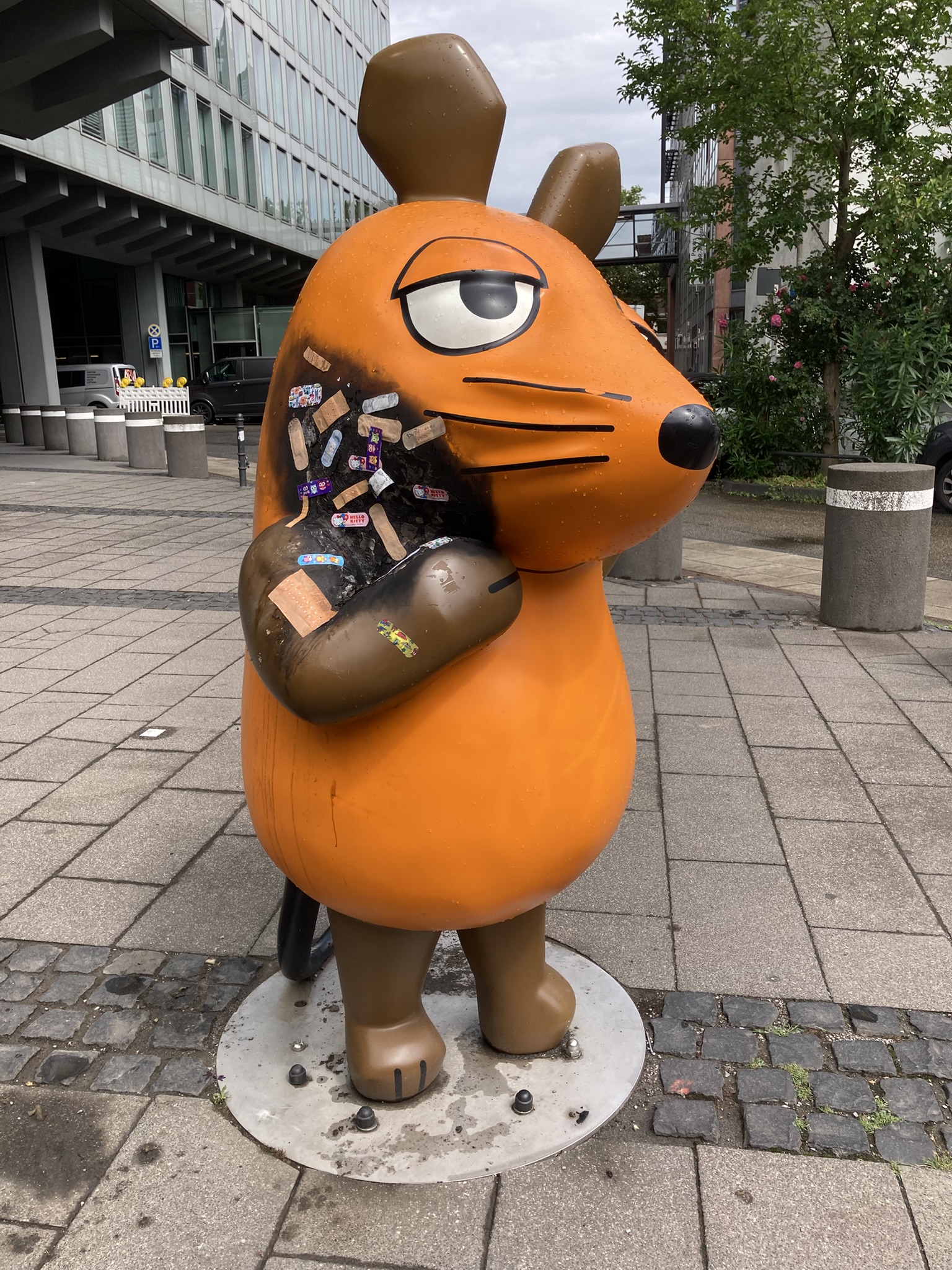 Nach dem mutmaßlichen Brandanschlag auf die Maus-Figur vor dem WDR-Gebäude in Köln sind mehrere Pflaster auf der verbrannten Stelle zu sehen.