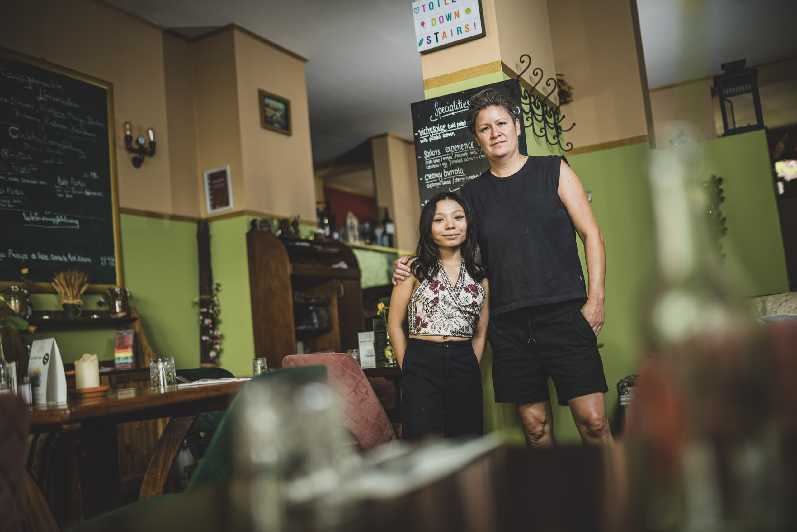 Surya Augustin steht neben ihrer zukünftigen Ausbilderin „Puk“ im Lokal „Jolie Restaurant + Cocktail & Wein“.