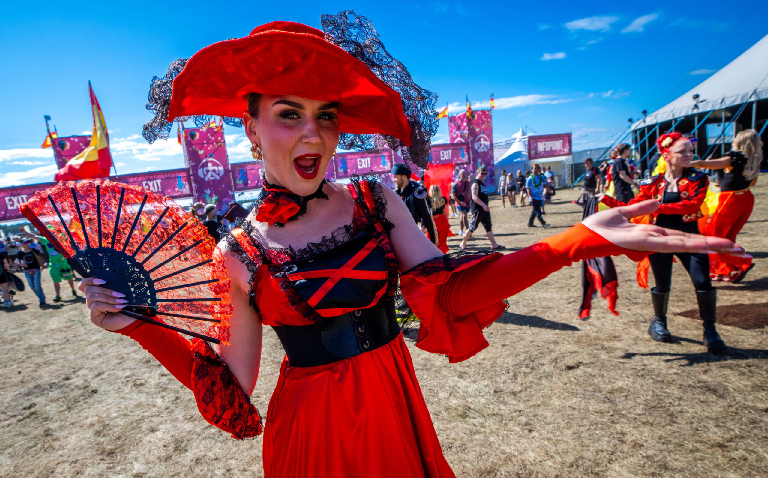 Eine Tänzerin in den spanischen Nationalfarben begrüßt am Eingang zum Airbeat One Festival die ersten Besucher auf dem Gelände des Musikfests.
