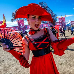 Eine Tänzerin in den spanischen Nationalfarben begrüßt am Eingang zum Airbeat One Festival die ersten Besucher auf dem Gelände des Musikfests.