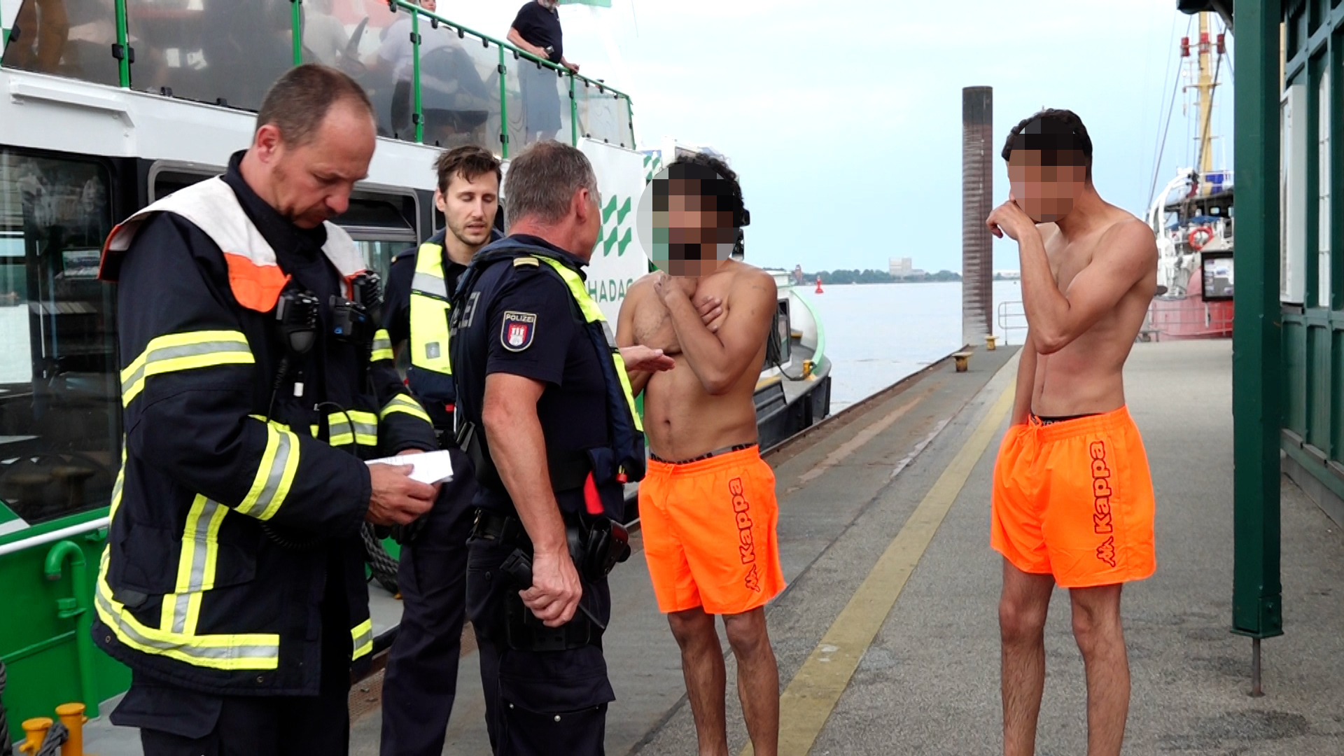 Die Polizisten stehen bei den zwei Schwimmern.