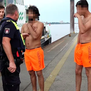 Die Polizisten stehen bei den zwei Schwimmern.