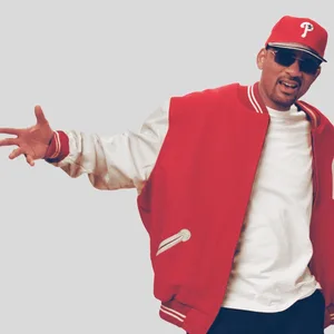 Er steht da mit Cap und Sonnenbrille und breitet die Arme aus