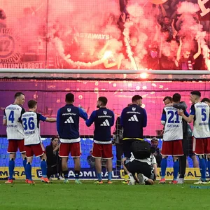 HSV-Profis vor der Nordtribüne, auf der Pyrotechnik gezündet wird