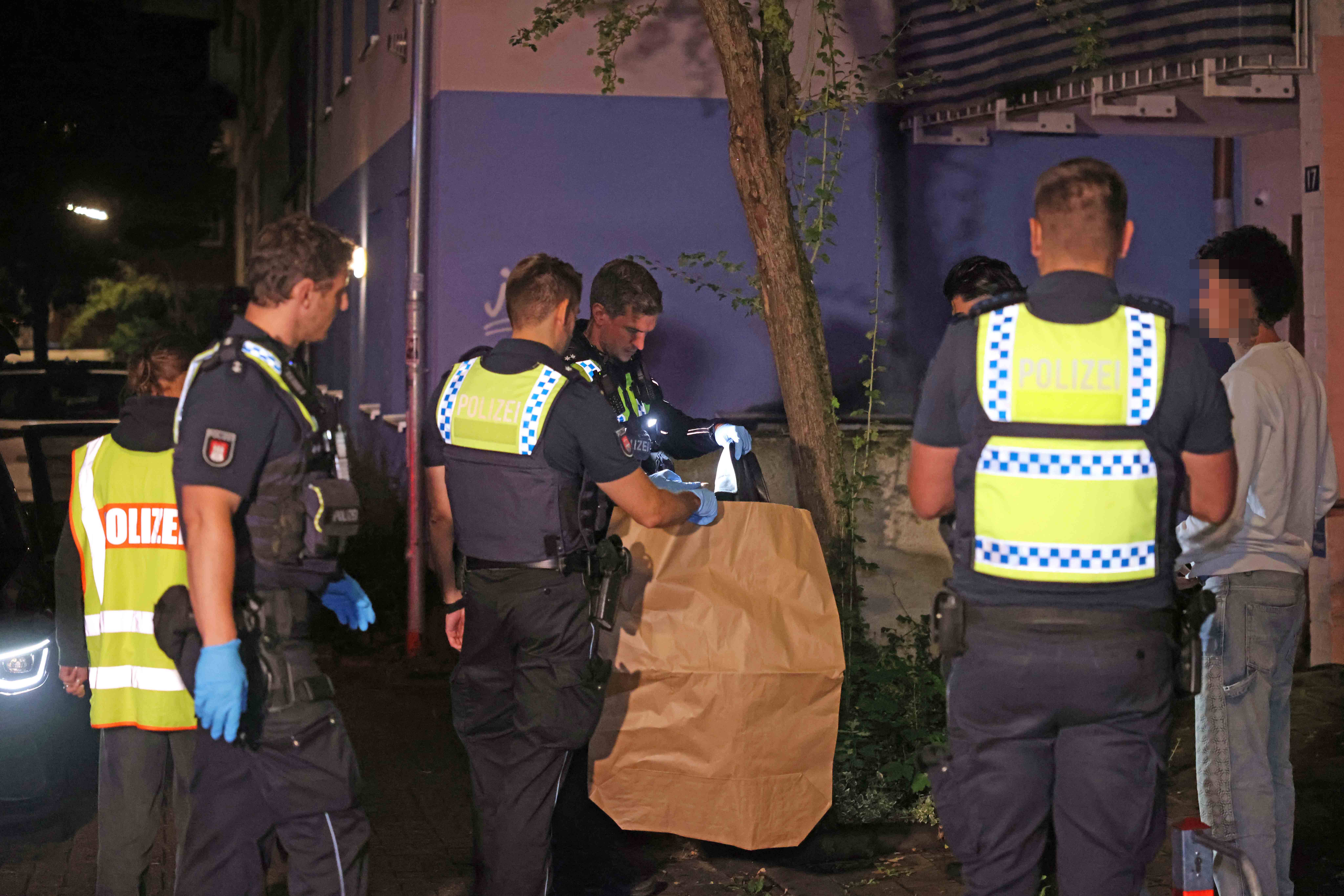 Polizisten stellen eine Jacke der Opfer sicher, um mögliche Spuren der Angreifer auf ihr zu finden.