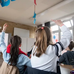 Schüler einer fünften Klasse eines Gymnasiums melden sich im Unterricht.