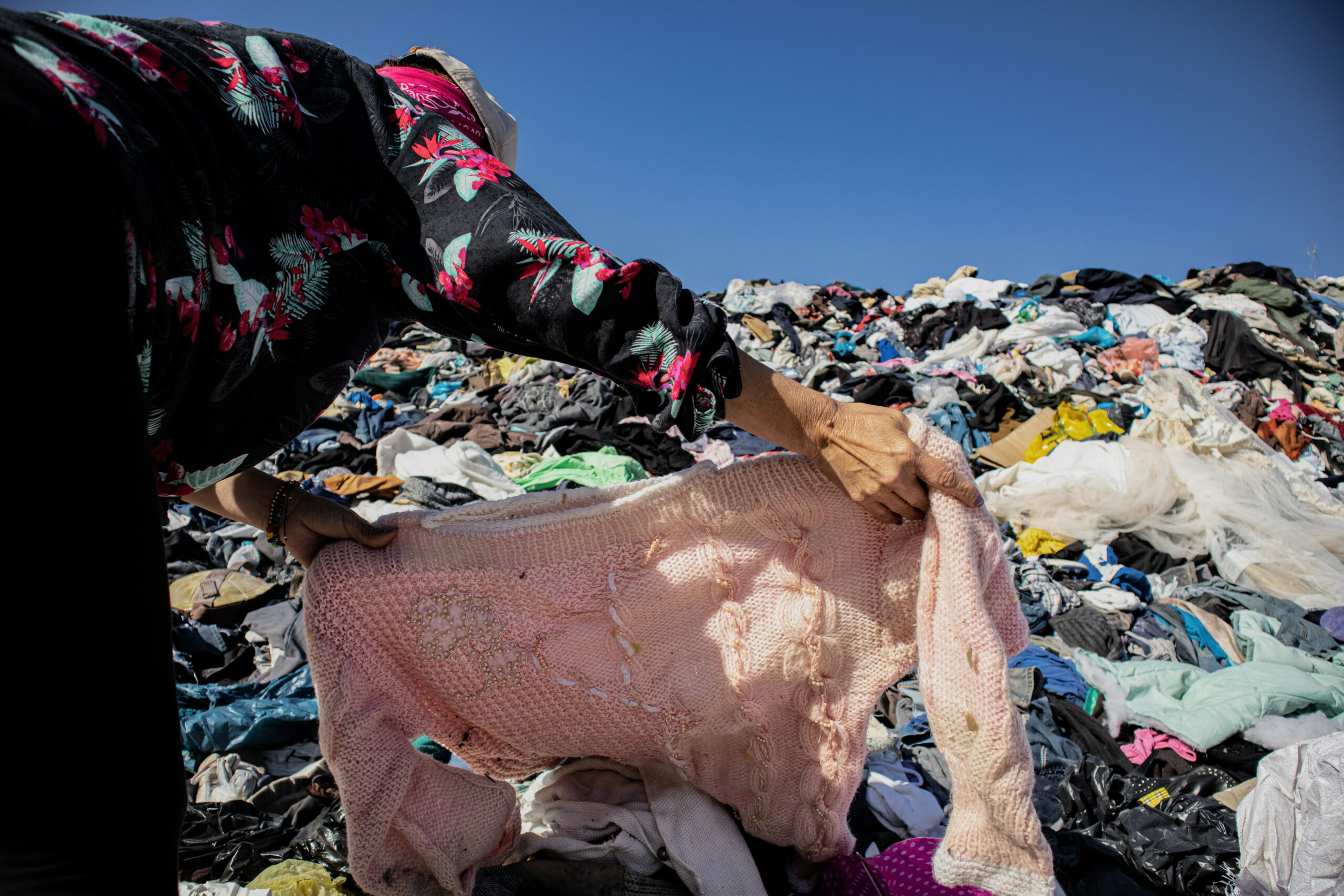 Eine Frau durchsucht einen Berg an Kleidung in der chilenischen Atacama-Wüste.