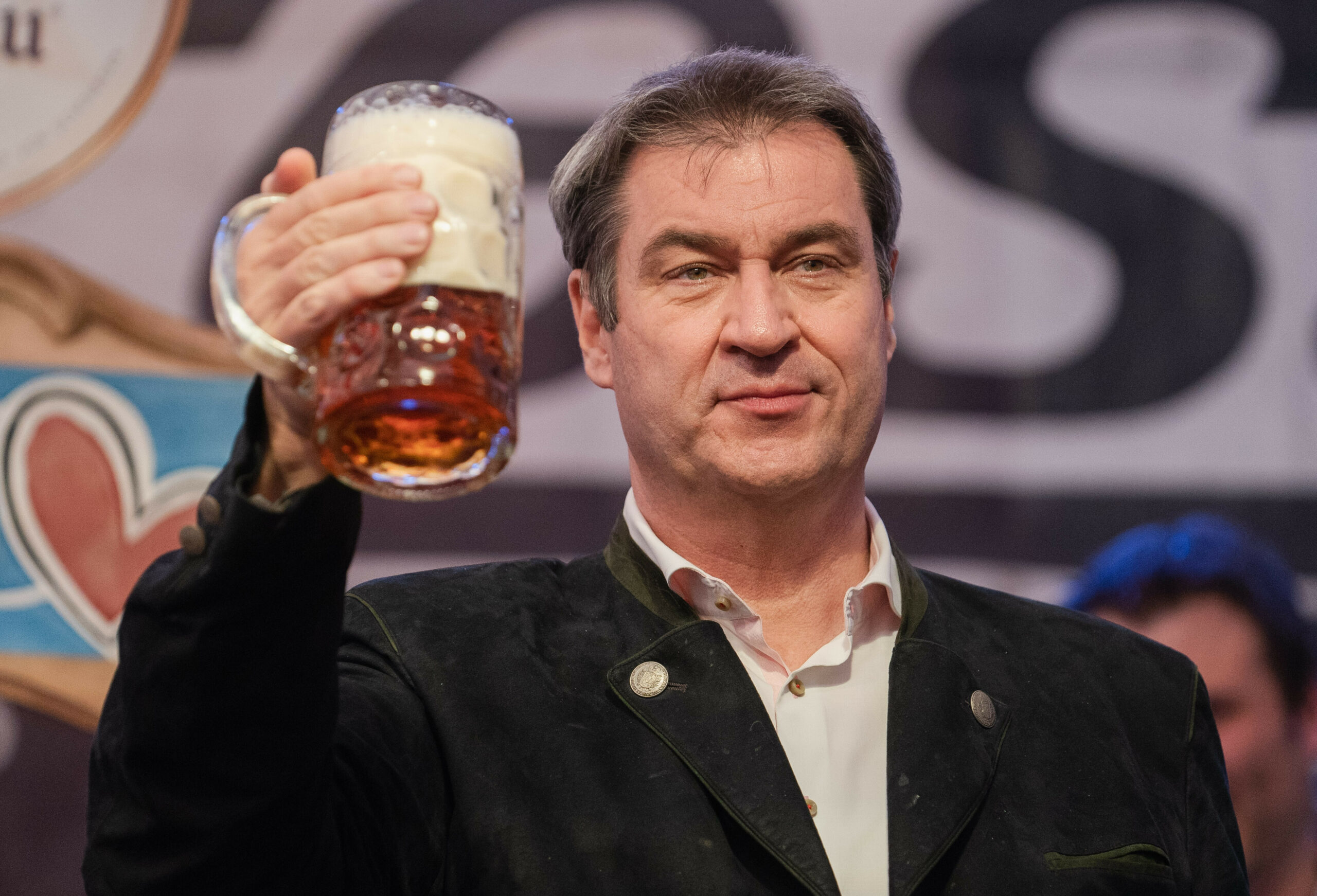 Der bayerische Ministerpräsident Markus Söder (CSU) hält auf der Bühne im Festzelt des Würzburger Frühlingsvolksfestes eine Maß Bier in der Hand.