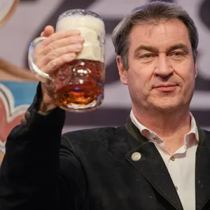 Der bayerische Ministerpräsident Markus Söder (CSU) hält auf der Bühne im Festzelt des Würzburger Frühlingsvolksfestes eine Maß Bier in der Hand.