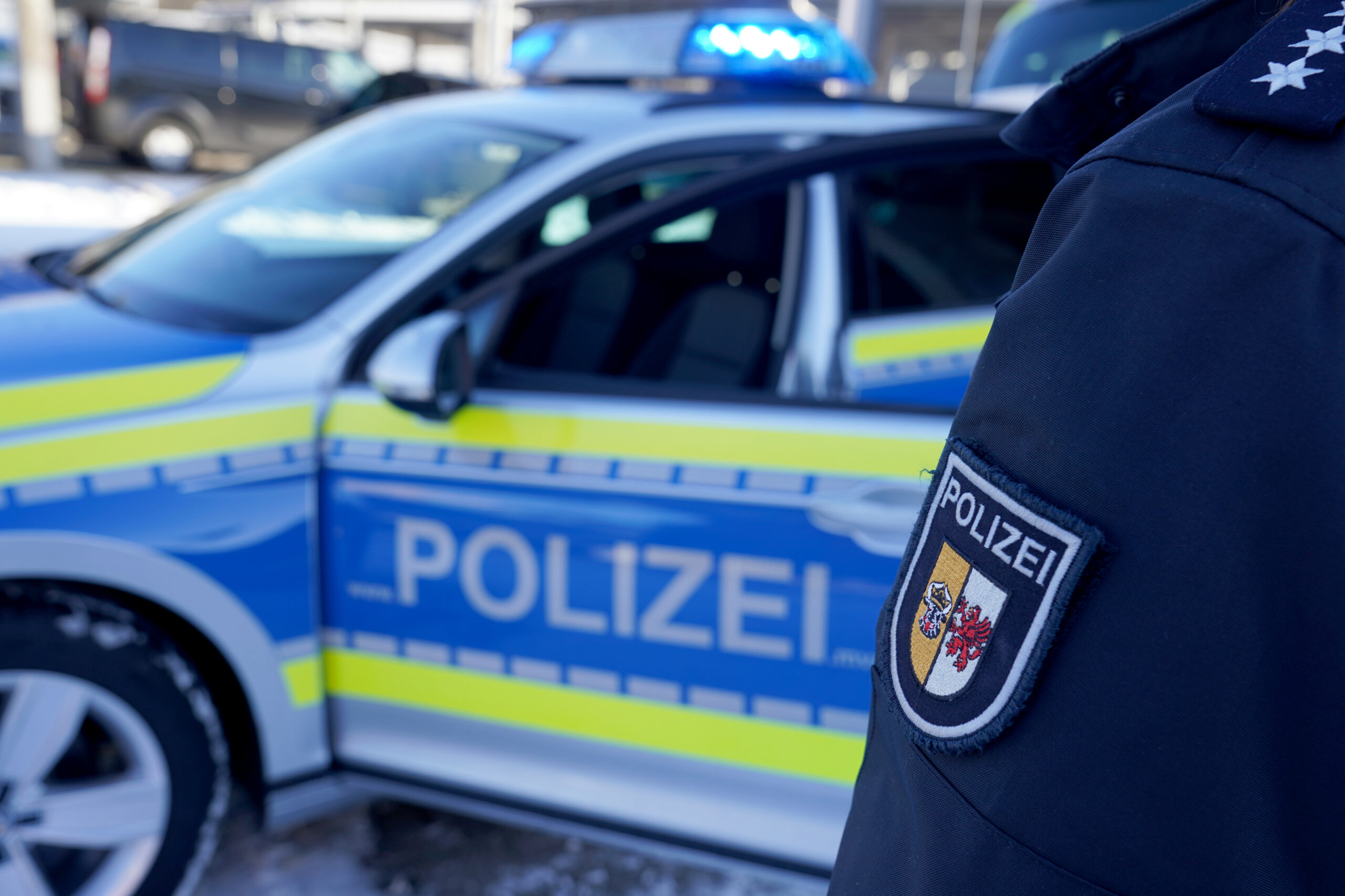 Eine Polizistin steht neben einem Einsatzfahrzeug.