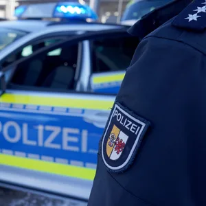 Eine Polizistin steht neben einem Einsatzfahrzeug.