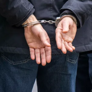 Ein Mann wird von zwei Polizisten festgenommen.