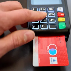 Mann gibt beim Bezahlen an der Kasse im Geschäft die PIN Geheimnummer in ein EC-Gerät ein.