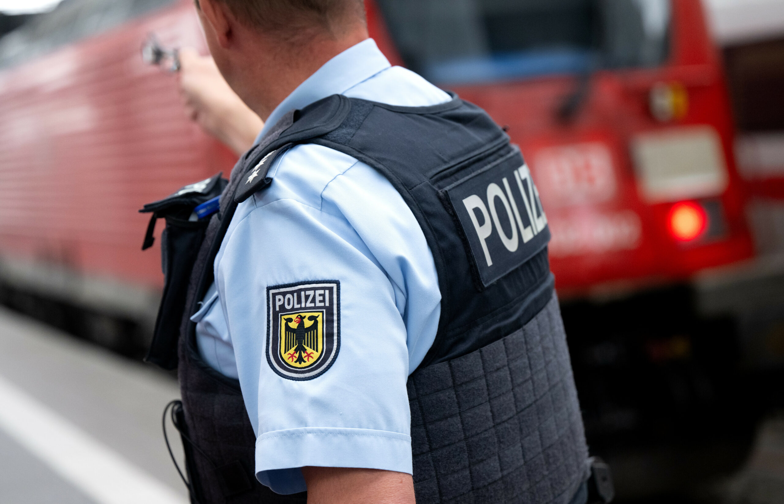 Bundespolizist steht an einem Bahnsteig vor einem Zug der Deutschen Bahn